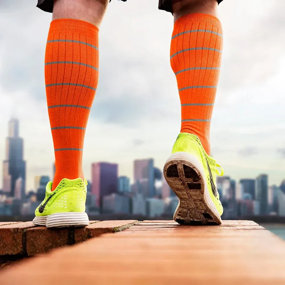 Man wearing orange and green striped compressed socks in front of city skyline